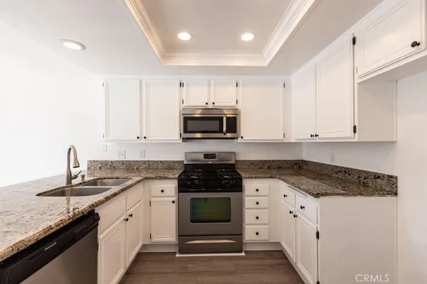 a kitchen with granite countertop white cabinets and black appliances