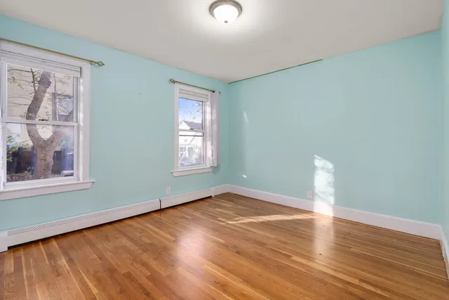 a view of an empty room with window and wooden floor