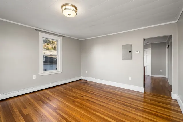 a view of an empty room with wooden floor and a window
