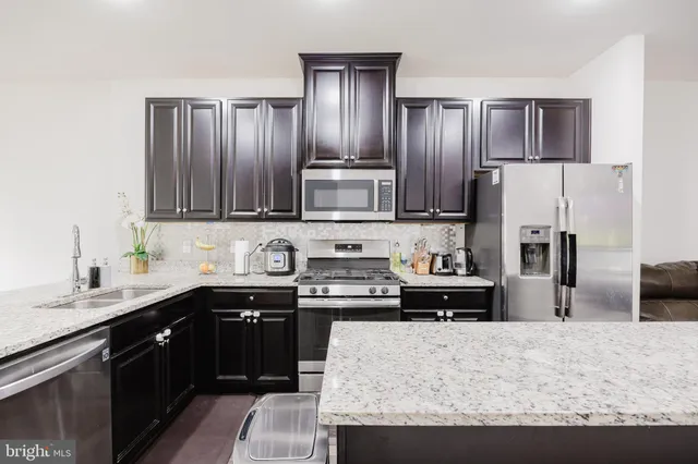 a kitchen with stainless steel appliances granite countertop a stove refrigerator and sink