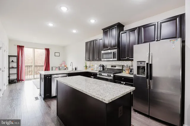 a kitchen with kitchen island granite countertop wooden cabinets a refrigerator and a stove