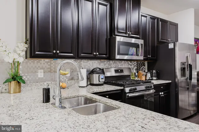 a kitchen with granite countertop wooden cabinets stainless steel appliances and a sink