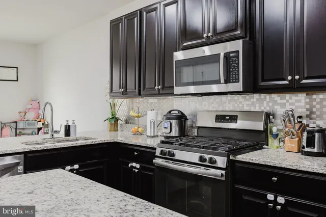 a kitchen with granite countertop a sink stainless steel appliances and cabinets