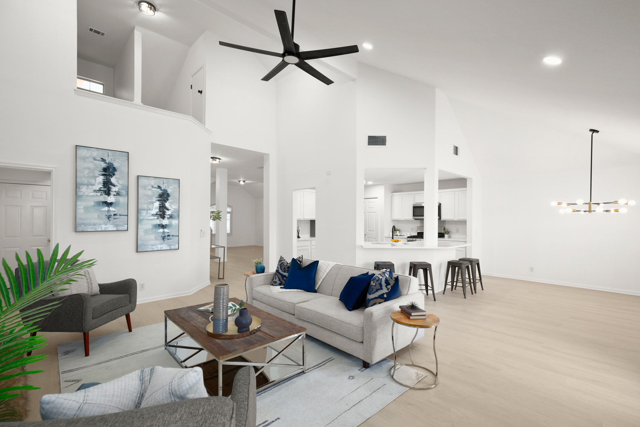 Living room featuring light wood-type flooring, a ceiling fan, lofted ceiling, and hanging lights