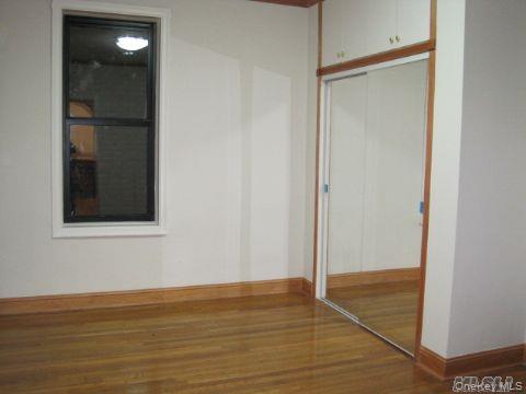 43-33 48th Street, Unit 1A Queens, NY 11104 - Photo 11 of 14 a view of an empty room with wooden floor and a mirror