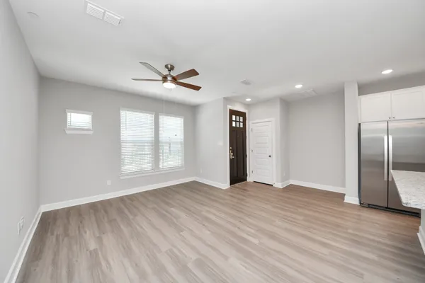 a view of an empty room with wooden floor and a window