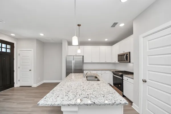 a kitchen with stainless steel appliances granite countertop a sink stove and white cabinets with wooden floor