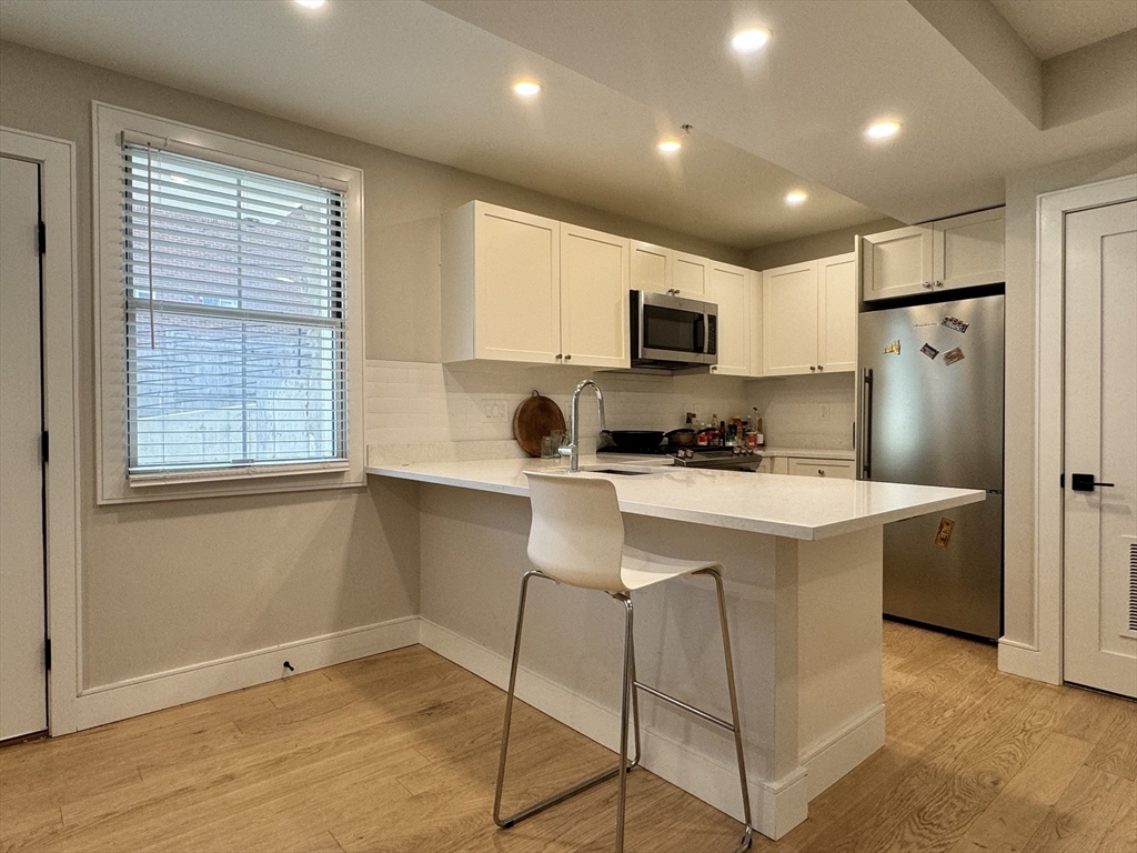 13 Greylock Road, Unit 1 Boston, MA 02134 - Photo 2 of 11 a kitchen with kitchen island a refrigerator stove and microwave