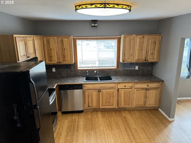 a kitchen with stainless steel appliances granite countertop wooden cabinets a sink and dishwasher with wooden floor
