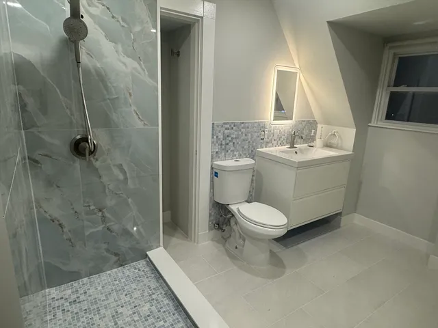 a bathroom with a granite countertop toilet a sink and a mirror