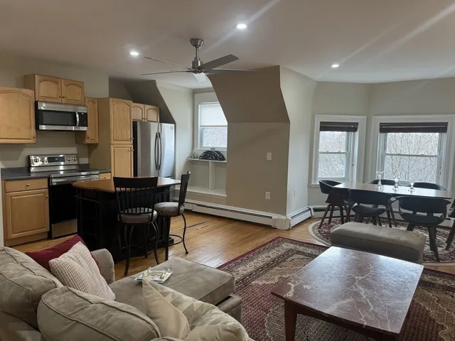 a living room with stainless steel appliances kitchen island granite countertop furniture and a wooden floor