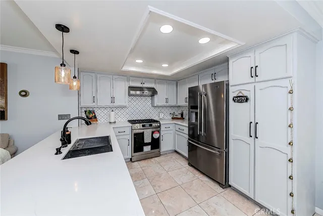 a large white kitchen with stainless steel appliances lots of counter space and windows