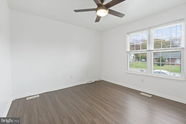 an empty room with a window and ceiling fan