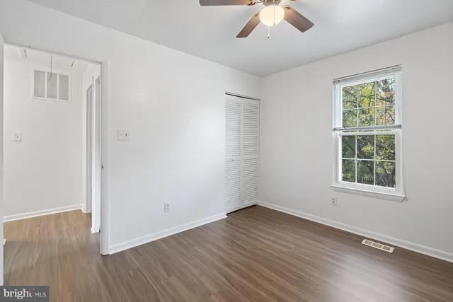 an empty room with a hardwood and ceiling fan
