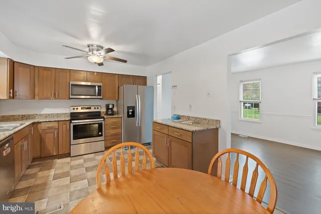 a kitchen with stainless steel appliances a stove a sink dishwasher a refrigerator with a dining table and chairs