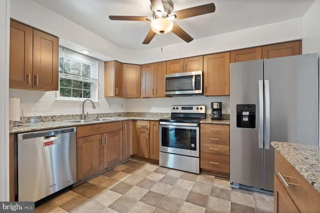 a kitchen with stainless steel appliances granite countertop a refrigerator a stove a sink and a microwave