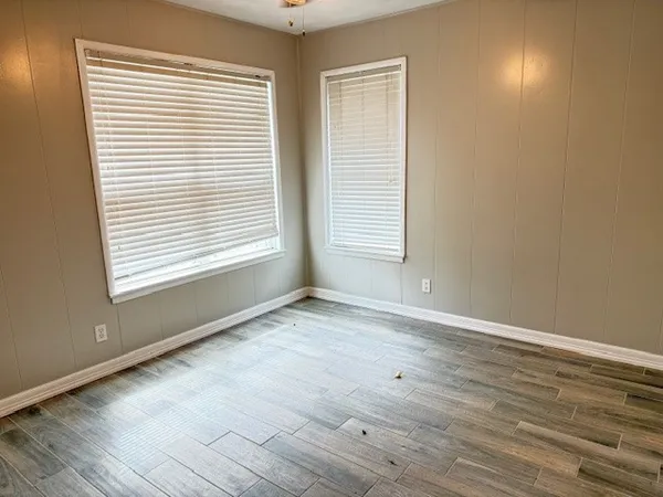 an empty room with wooden floor and windows