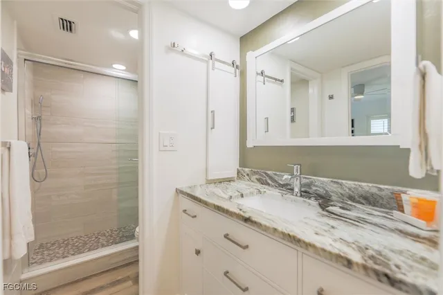 a bathroom with a granite countertop sink mirror and shower