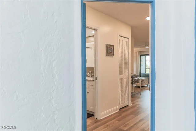 a view of a hallway with wooden floor and a bathroom
