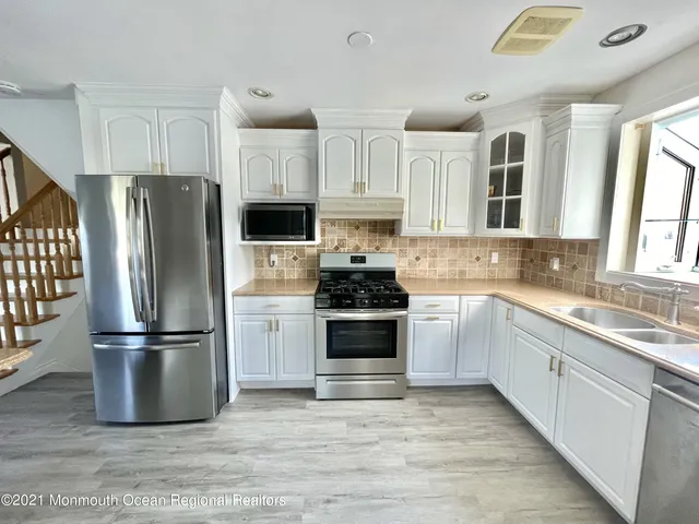 a kitchen with granite countertop a refrigerator stove and sink