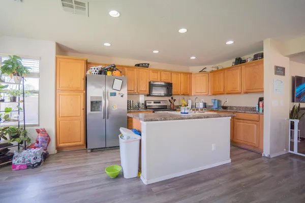 a kitchen with stainless steel appliances granite countertop a refrigerator a sink and a stove with wooden floor