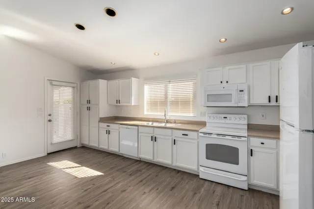 a large white kitchen with granite countertop a white stove a sink and white refrigerator