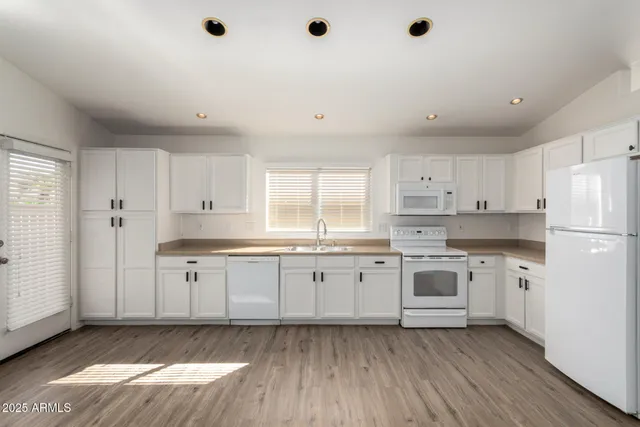 a kitchen with granite countertop white cabinets and white appliances