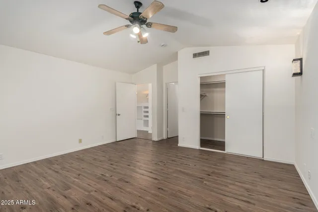 an empty room with wooden floor fan and windows