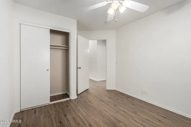 an empty room with wooden floor fan and windows