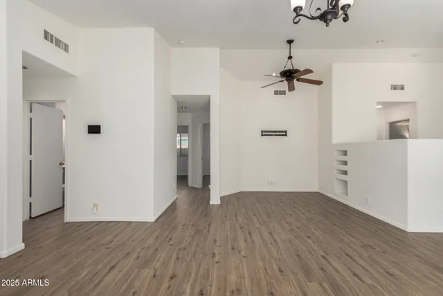 a view of an empty room with window and chandelier
