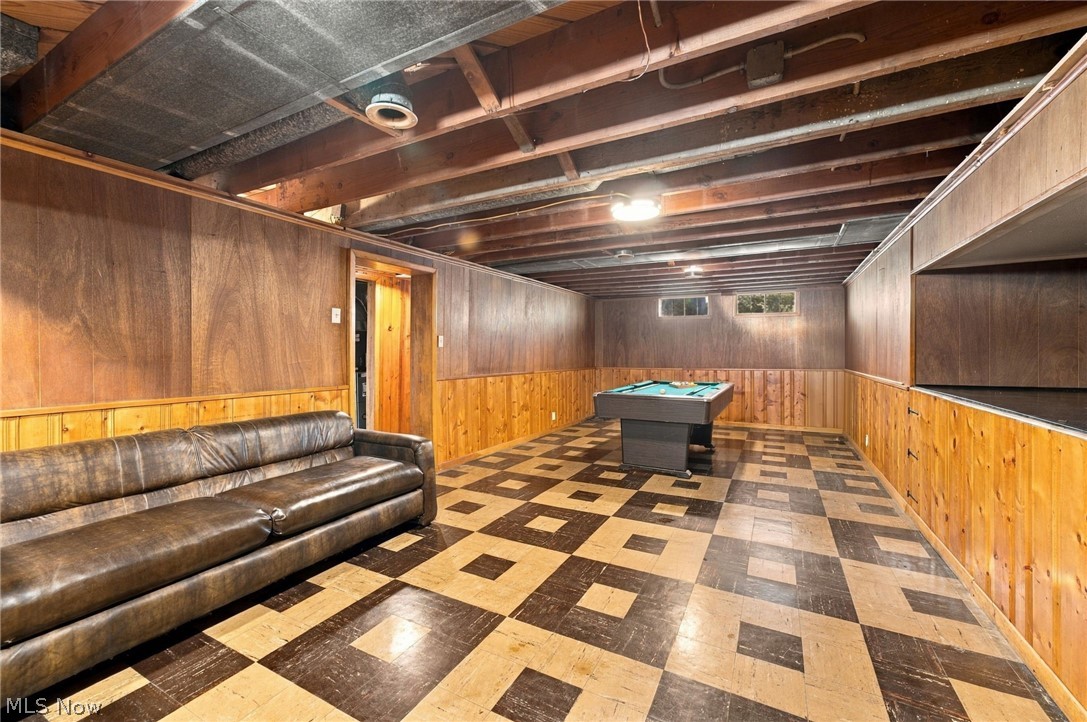 1434 Sunset Road Mayfield Heights, OH 44124 - Photo 9 of 36 Finished basement recreation space featuring wood-paneled walls, geometric patterned flooring in contrasting tones, exposed beam ceiling with recessed lighting, leather seating, and built-in pool table for entertainment