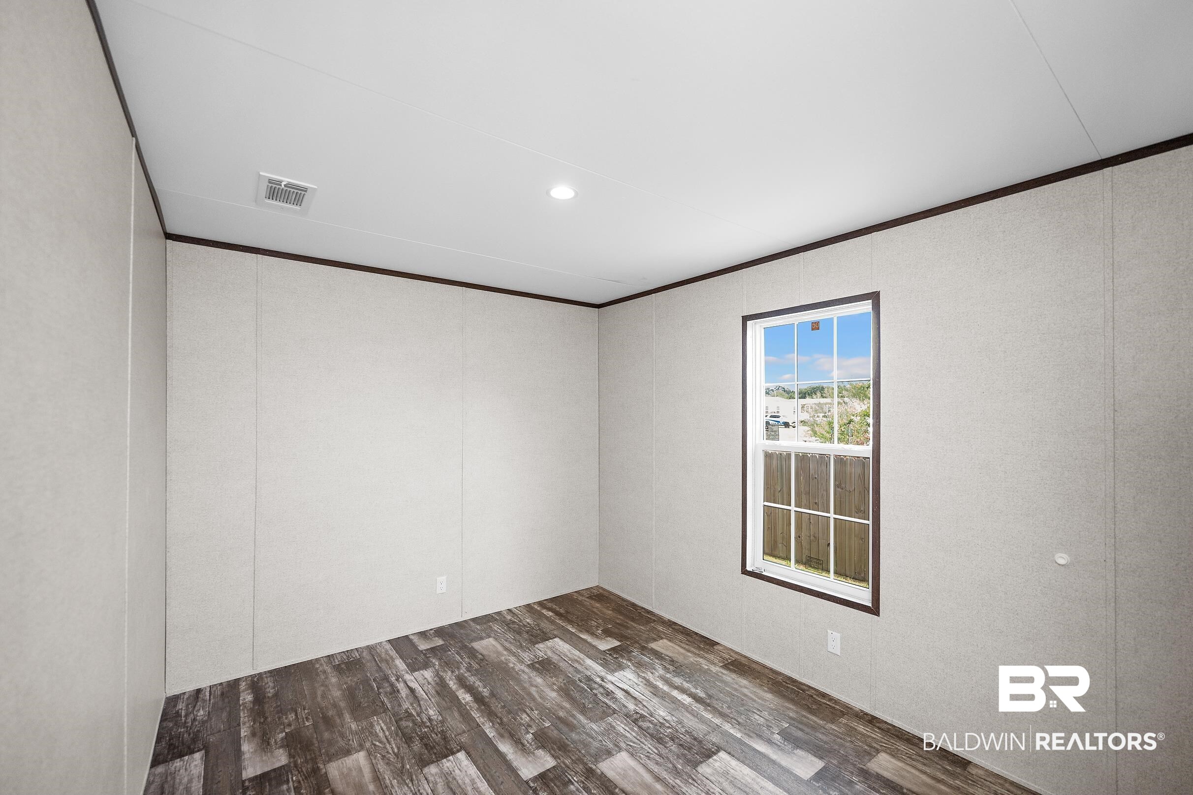 21601 Westside Loop Silverhill, AL 36576 - Photo 29 of 42 Room featuring wood-finish flooring, a single-pane window with dark trim, recessed ceiling lighting, and a white electrical outlet
