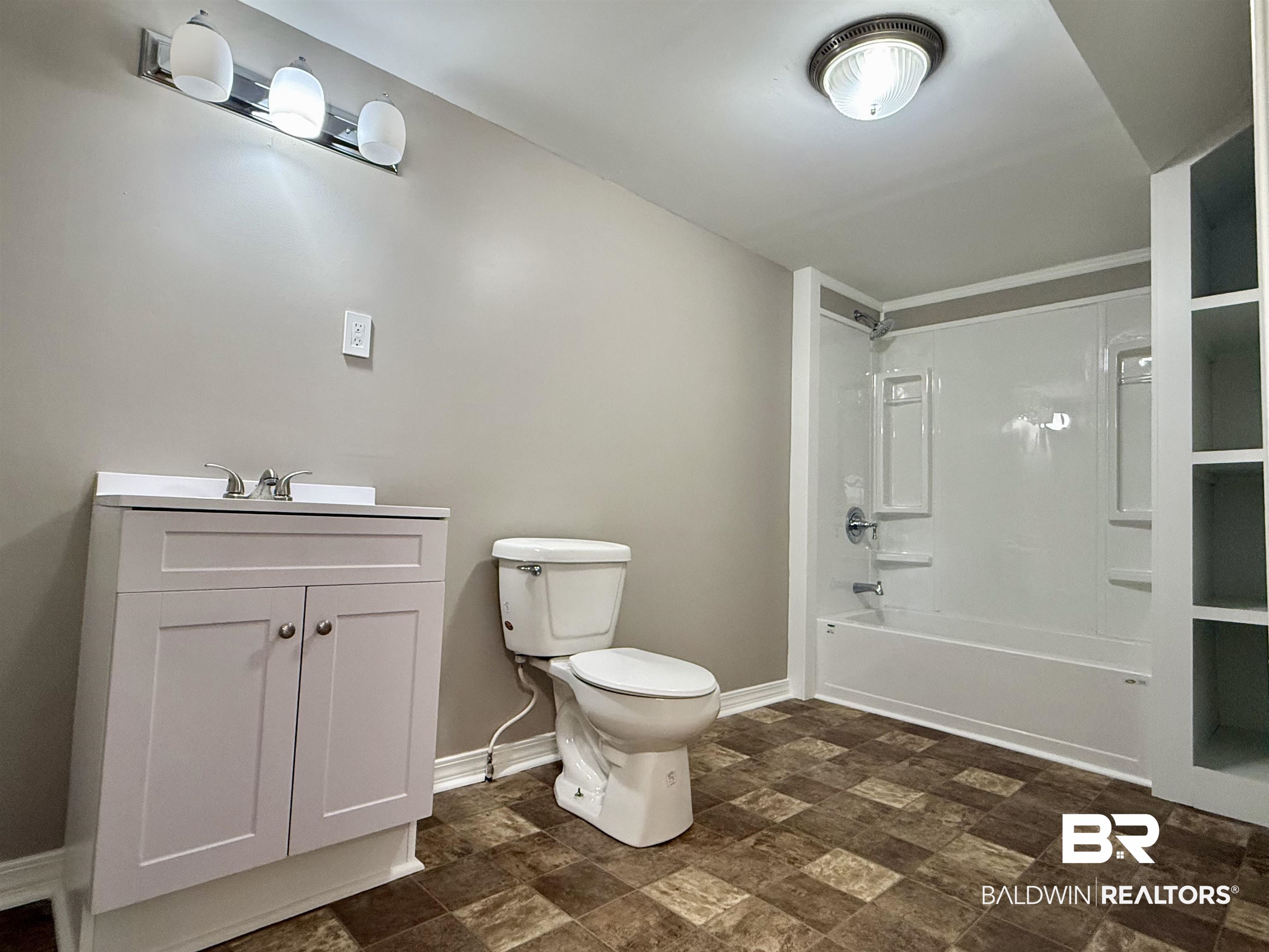 205 Schad Street Brewton, AL 36426 - Photo 10 of 11 Bathroom with stone finish flooring, vanity, and shower / bathtub combination