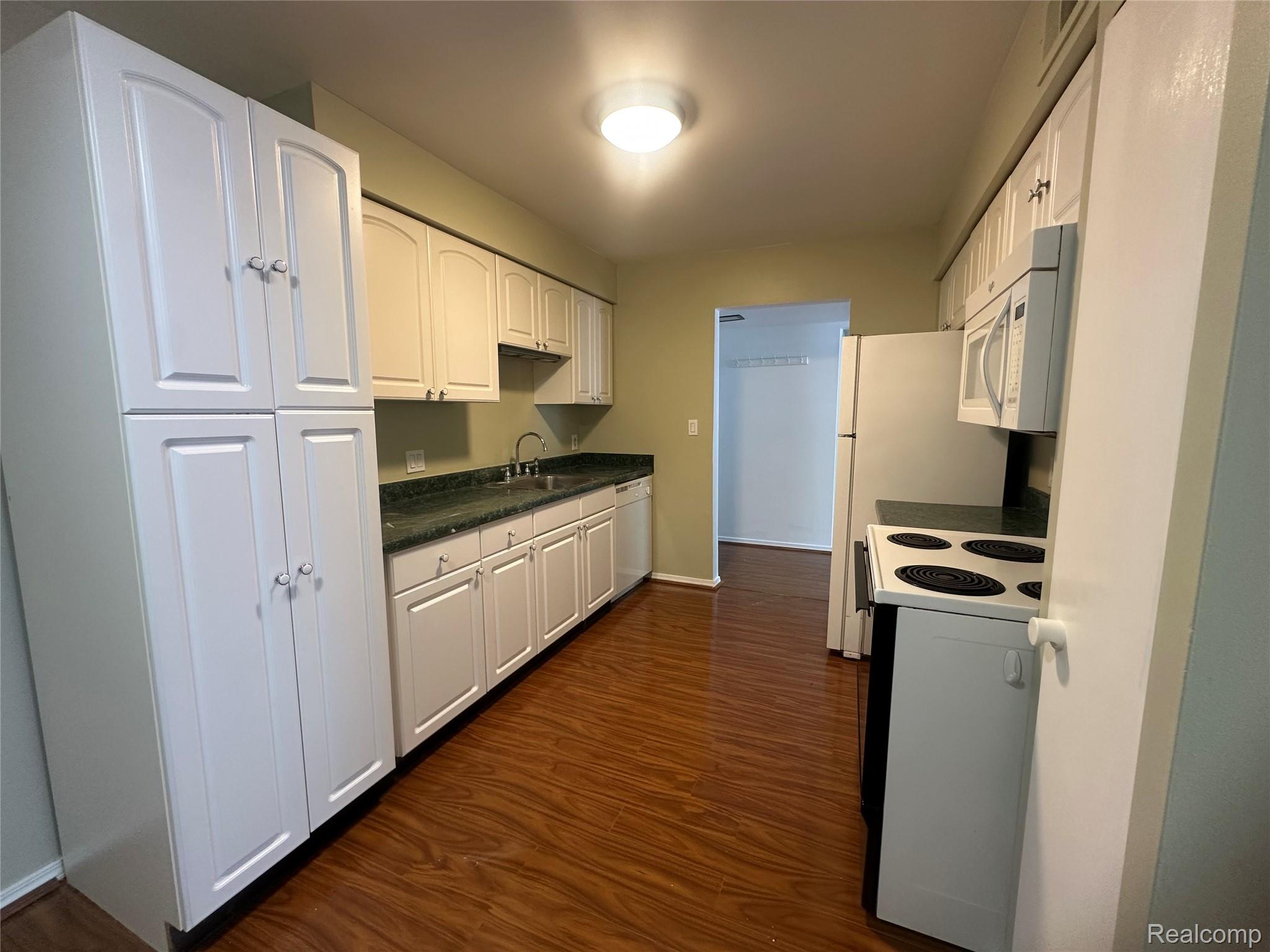 509 East University Drive Rochester, MI 48307 - Photo 8 of 20 Kitchen featuring white appliances, dark wood finished floors, dark countertops, and white cabinets