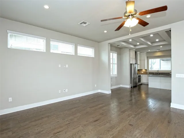an empty room with wooden floor and a ceiling fan