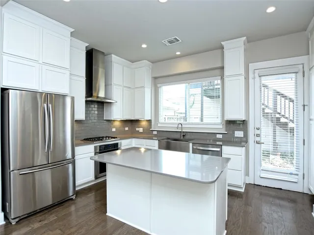 a kitchen with stainless steel appliances a sink a stove a refrigerator and cabinets