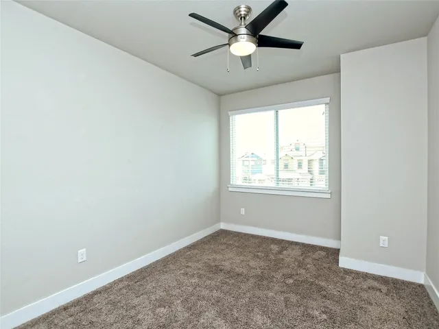 an empty room with a window and a fan