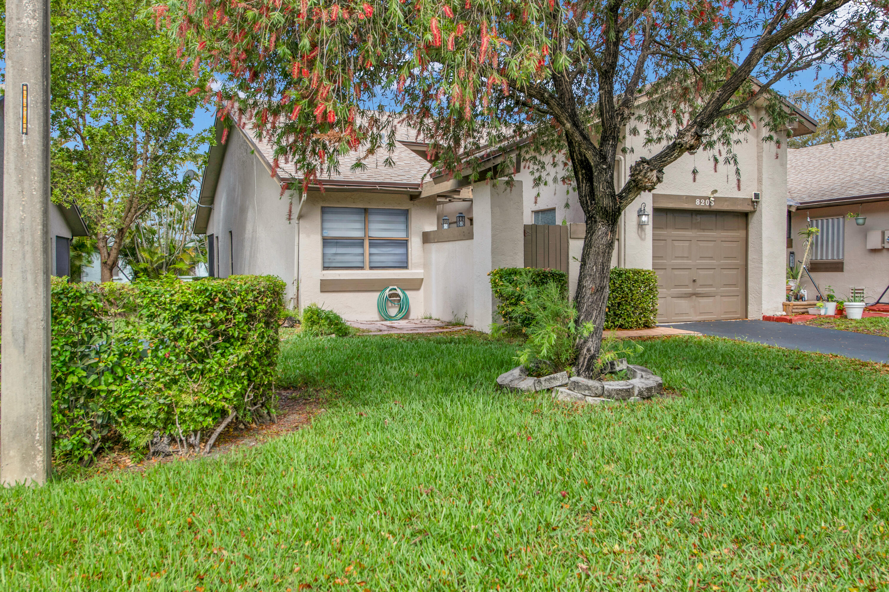 8203 Northwest 100th Way Tamarac, FL 33321 - Photo 4 of 31 a front view of a house with a garden and tree