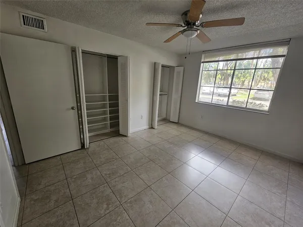 an empty room with windows and fan