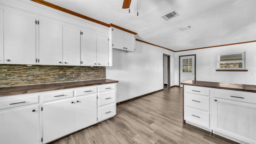 760 College Farm Road Stephenville, TX 76401 - Photo 11 of 32 a kitchen with granite countertop white cabinets and wooden floor