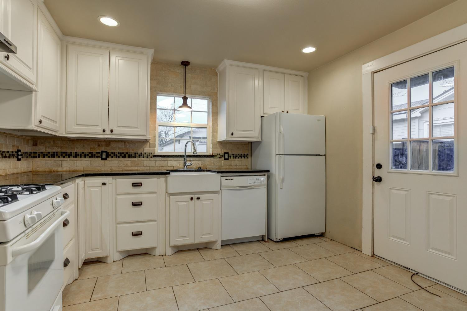3415 27th Street Lubbock, TX 79410 - Photo 11 of 30 a kitchen with granite countertop white cabinets and refrigerator