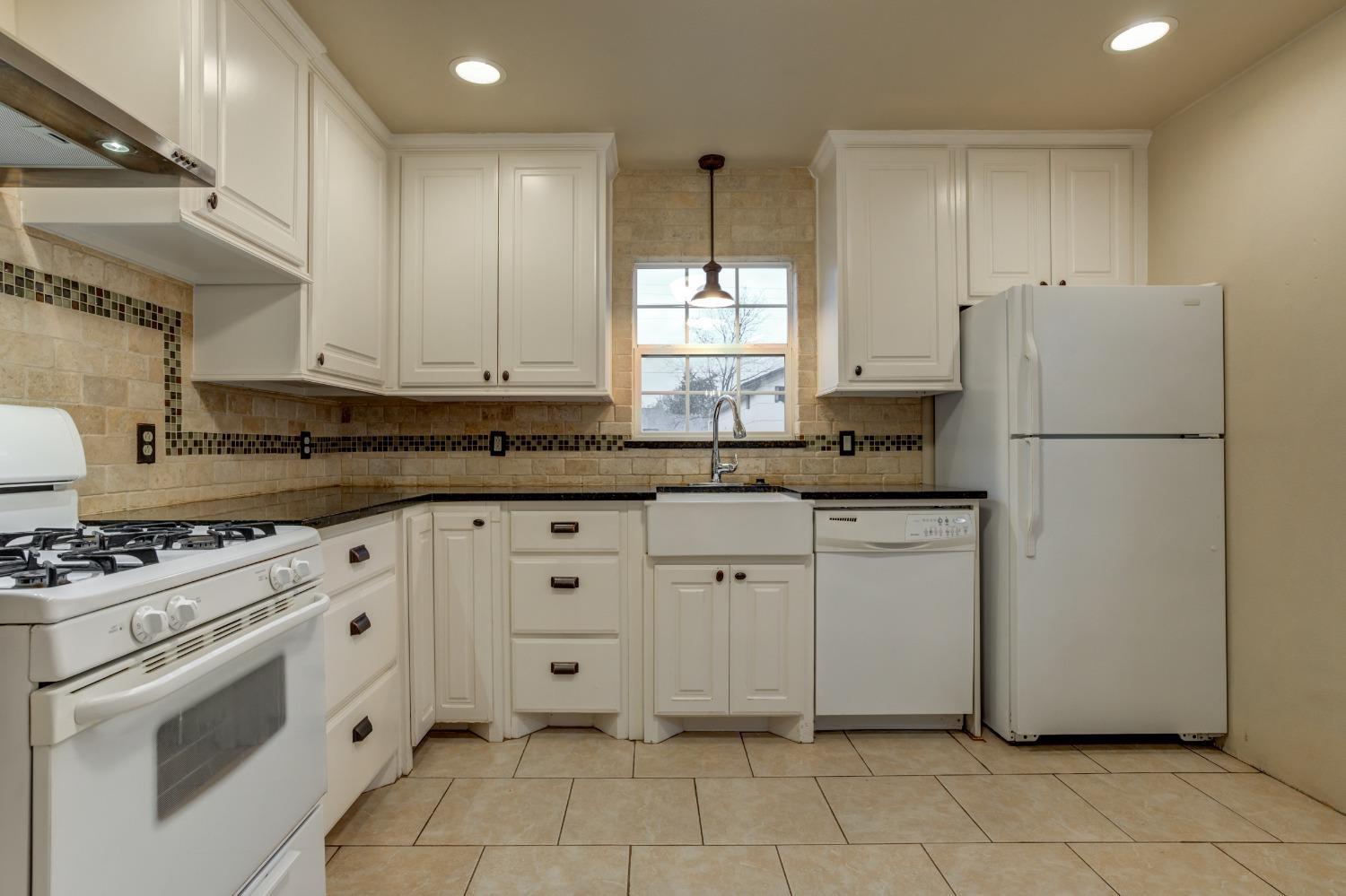 3415 27th Street Lubbock, TX 79410 - Photo 17 of 30 a kitchen with white cabinets and white appliances