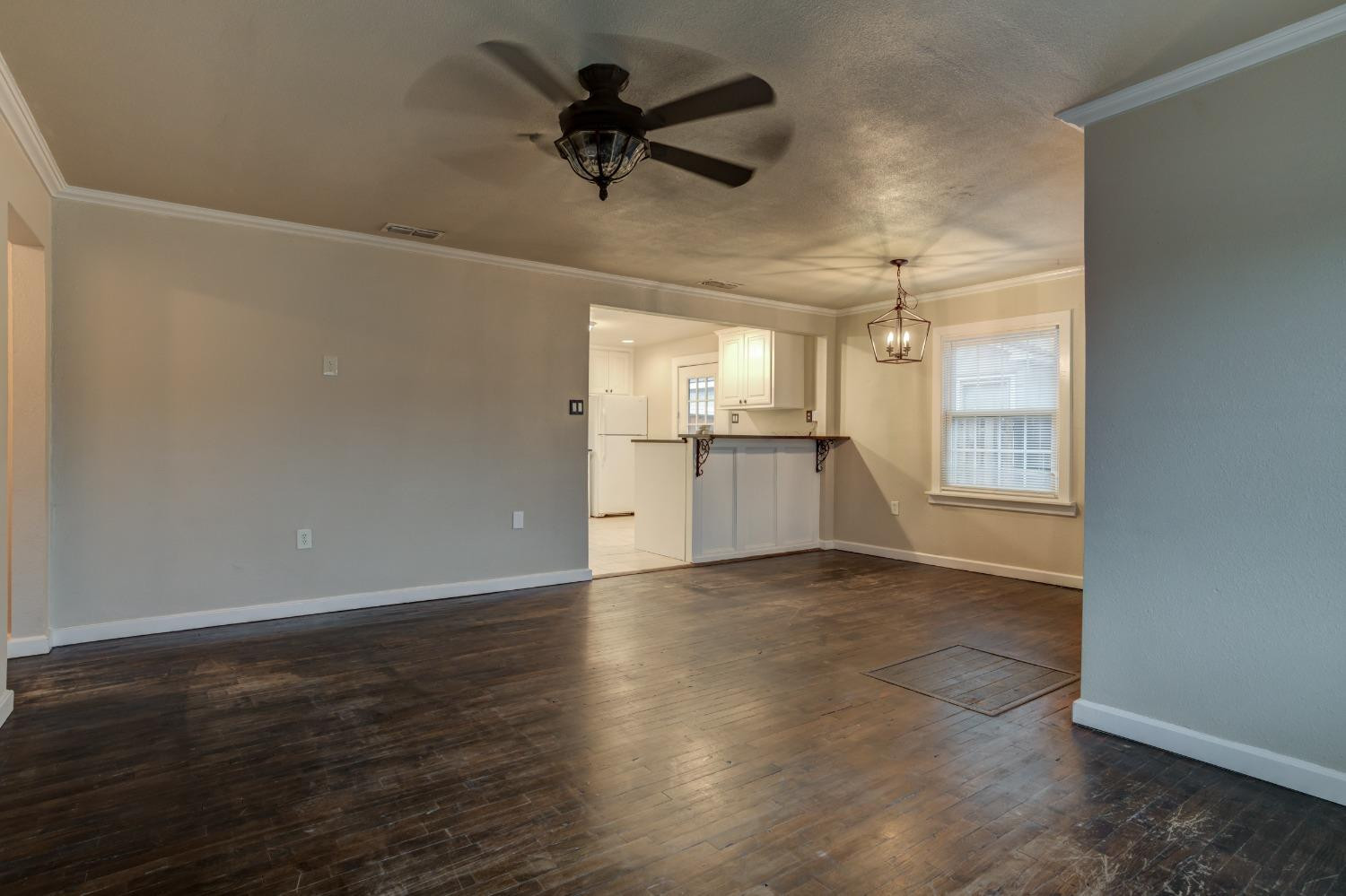 3415 27th Street Lubbock, TX 79410 - Photo 4 of 30 an empty room with wooden floor ceiling fan and windows