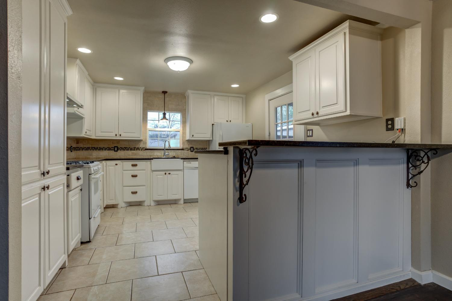 3415 27th Street Lubbock, TX 79410 - Photo 10 of 30 a kitchen with stainless steel appliances granite countertop a refrigerator a sink dishwasher and white cabinets with wooden floor