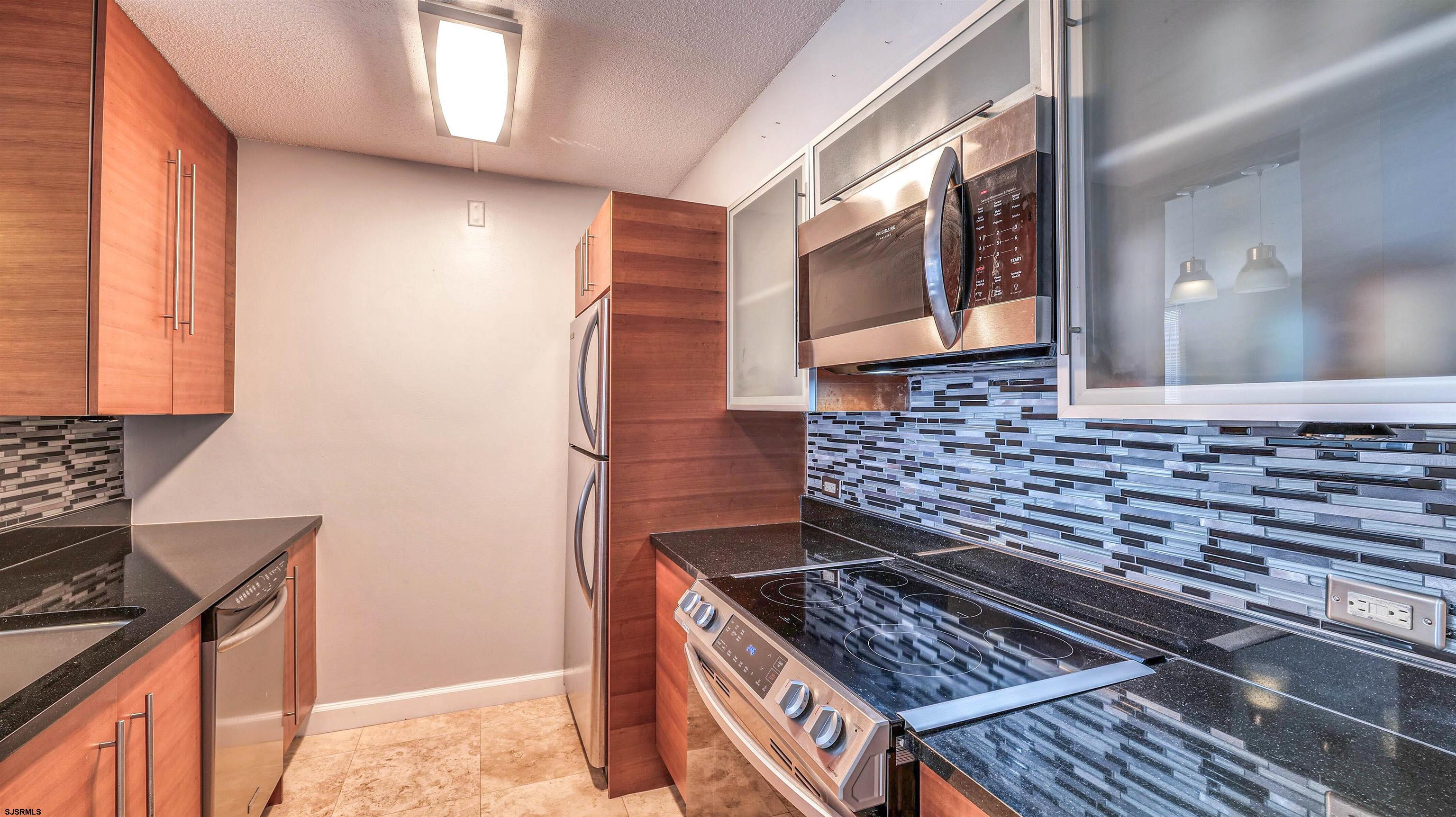 526 Pacific Avenue, Unit 903 Atlantic City, NJ 08401 - Photo 16 of 43 a kitchen with stainless steel appliances granite countertop a stove and a microwave