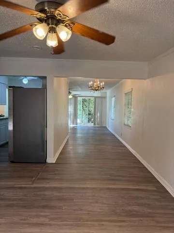 a view of an empty room with wooden floor and a ceiling fan