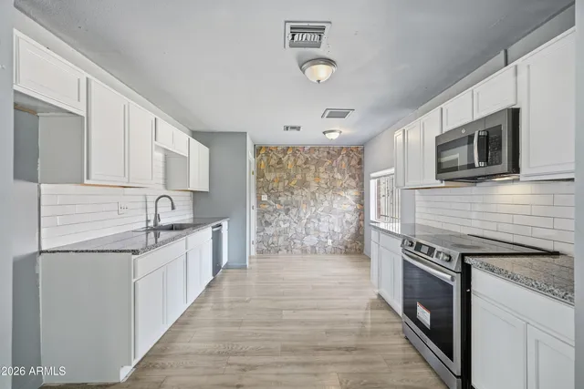 a kitchen with stainless steel appliances granite countertop a sink stove and refrigerator