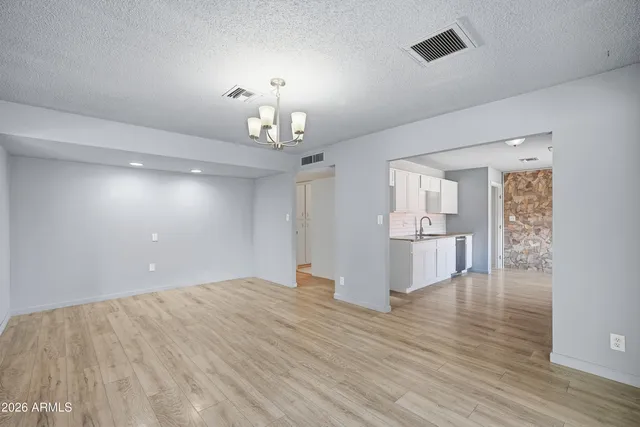 an empty room with a chandelier fan and windows