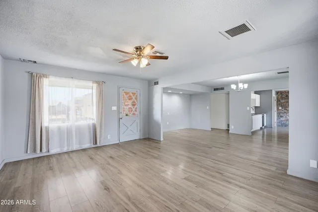 a view of an empty room with window and wooden floor