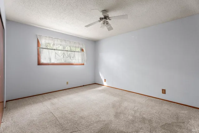 an empty room with windows and ceiling fan
